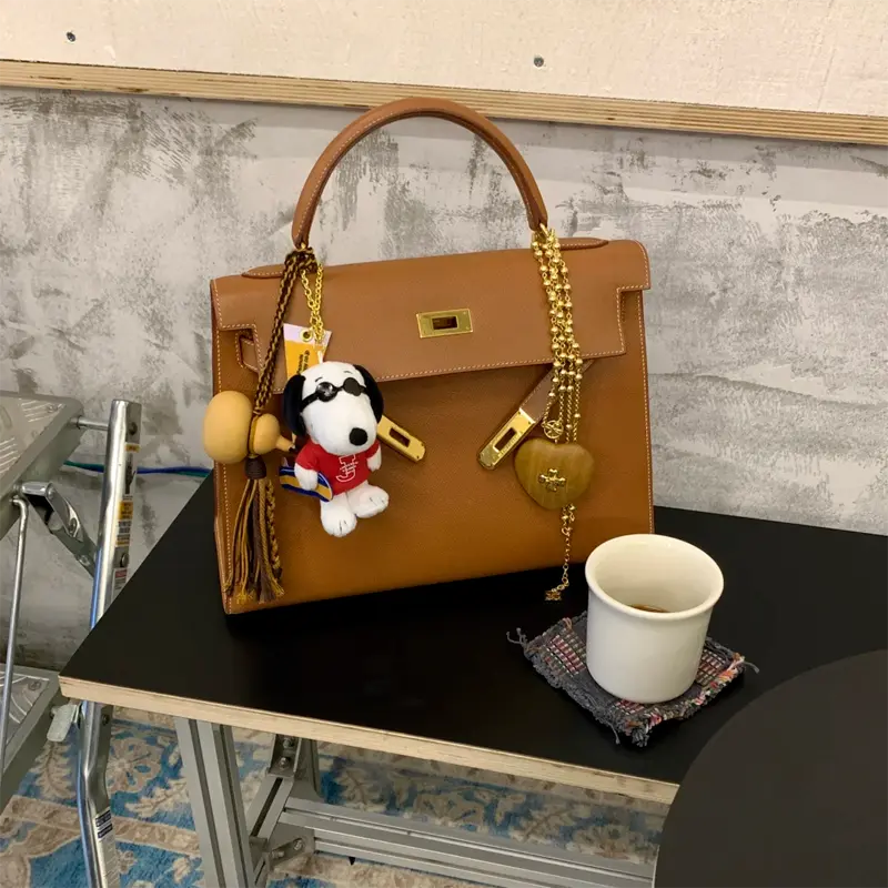 Gold Epsom Replica Kelly 32cm: Rain-Resistant & Structured Replica Hermes Kelly 32cm in Gold Epsom leather at café - structured shape holds perfectly