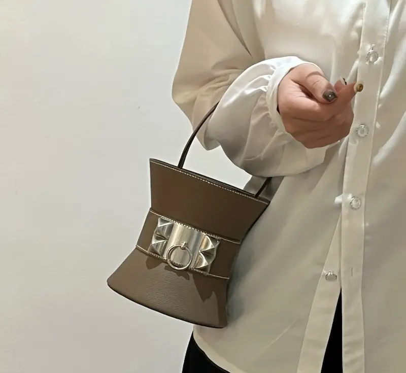 Hermes Mini Medor étoupe as evening clutch Close-up of étoupe grey Mini Medor replica bag being held as clutch