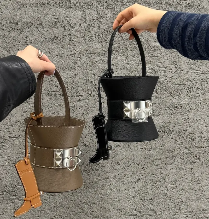 Holding the replica Hermes Mini Medor Stylist hand carrying black Epsom leather Mini Medor replica bag by its chain strap
