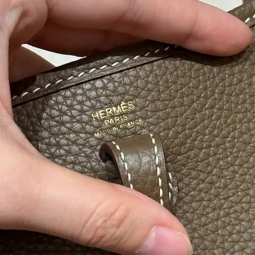 Authentic Hermes Perforated H Logo Replica Detail Closeup of perforated H logo on Hermes Evelyne TPM replica flap interior