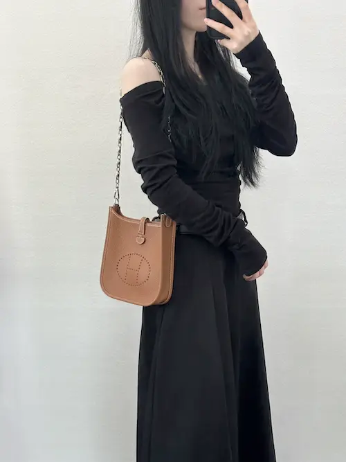 Gold Hermes Evelyne 16 Replica Crossbody Lifestyle Shot Woman wearing gold Hermes Evelyne TPM replica crossbody bag with casual outfit