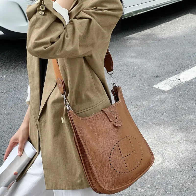 Style the Gold Replica Evelyne 29 Crossbody Woman carrying Gold Clemence leather replica Hermes Evelyne 29 crossbody bag in city